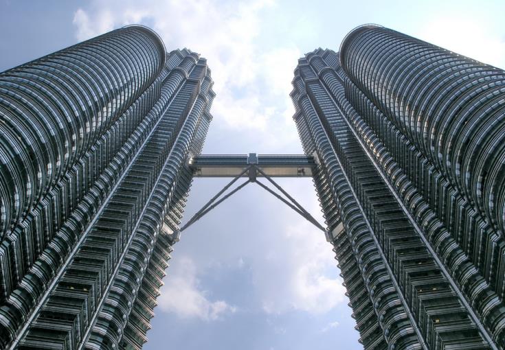 Looking up at the Petronas Twin Towers skybridge from ground level showing the double-decker steel and glass connection
